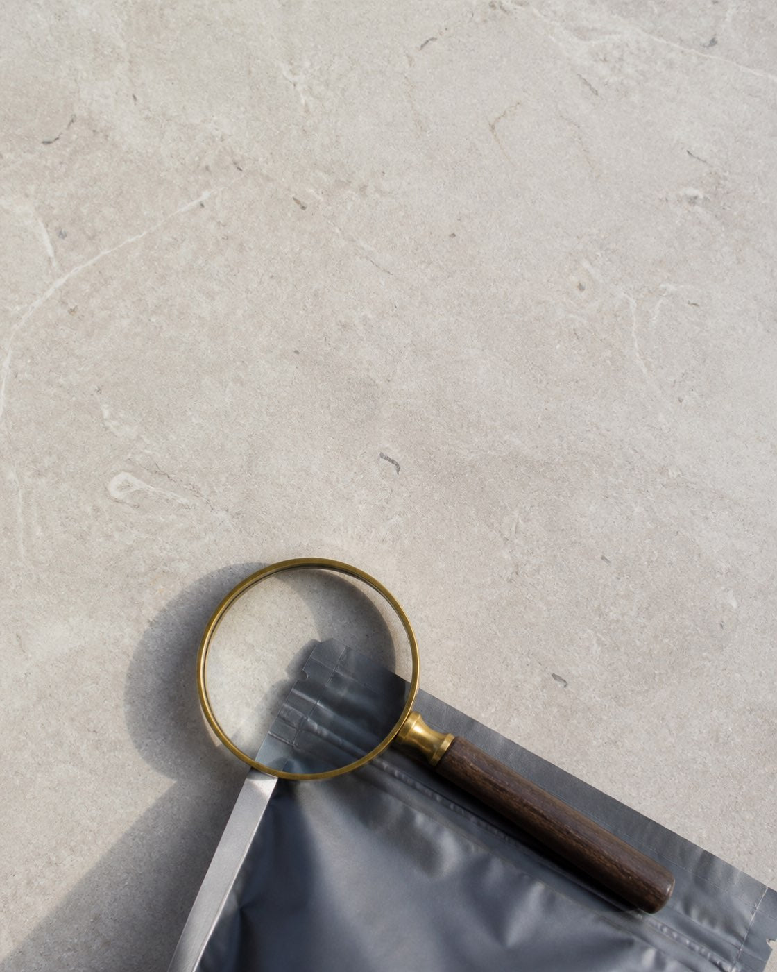 A supplement label being read closely through a magnifying glass on a plain surface