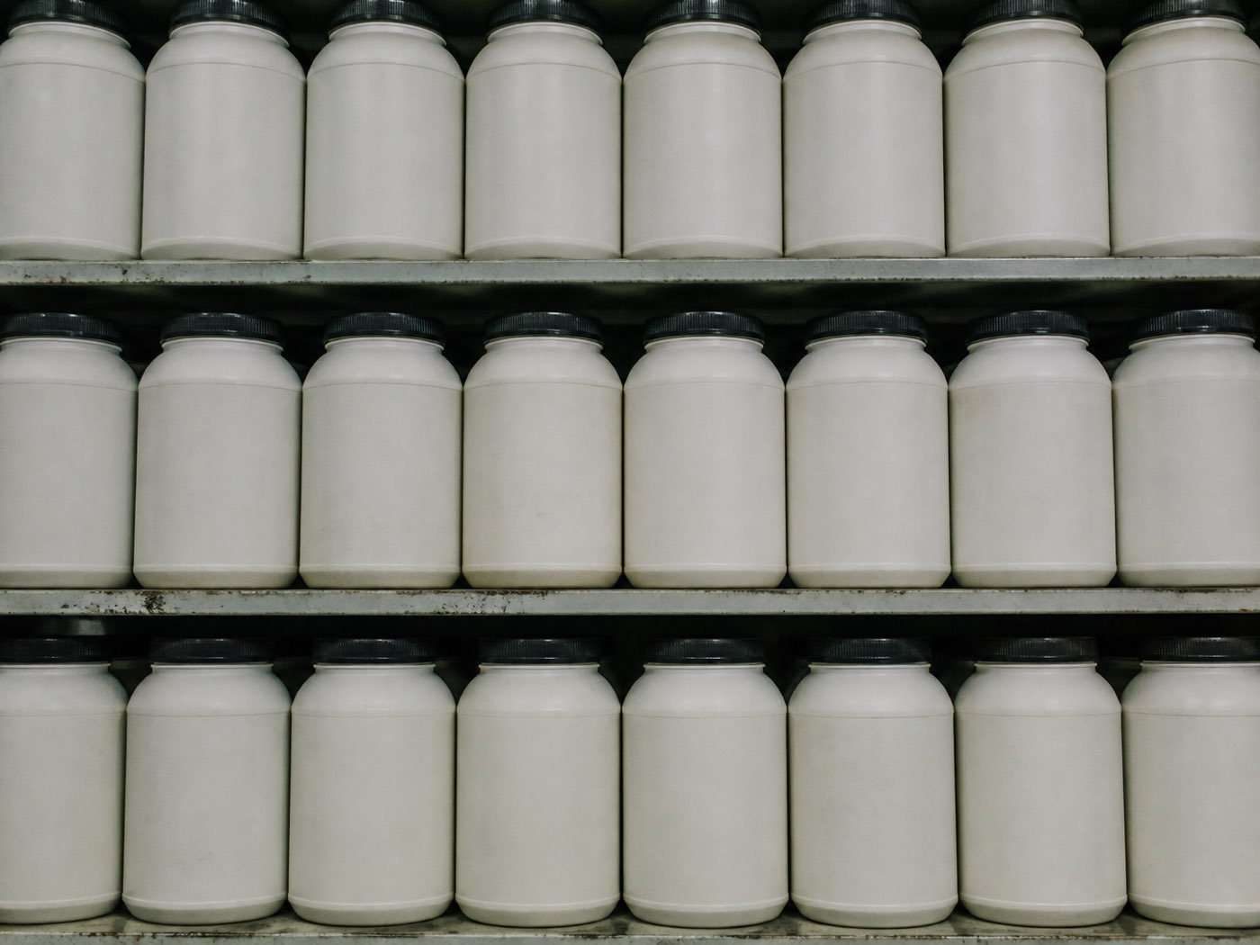 A crowded supplement shelf in a shop, many similar tubs side by side