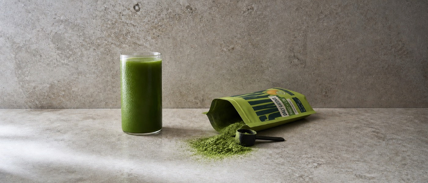 A filled glass beside an open pouch with powder spilled across stone
