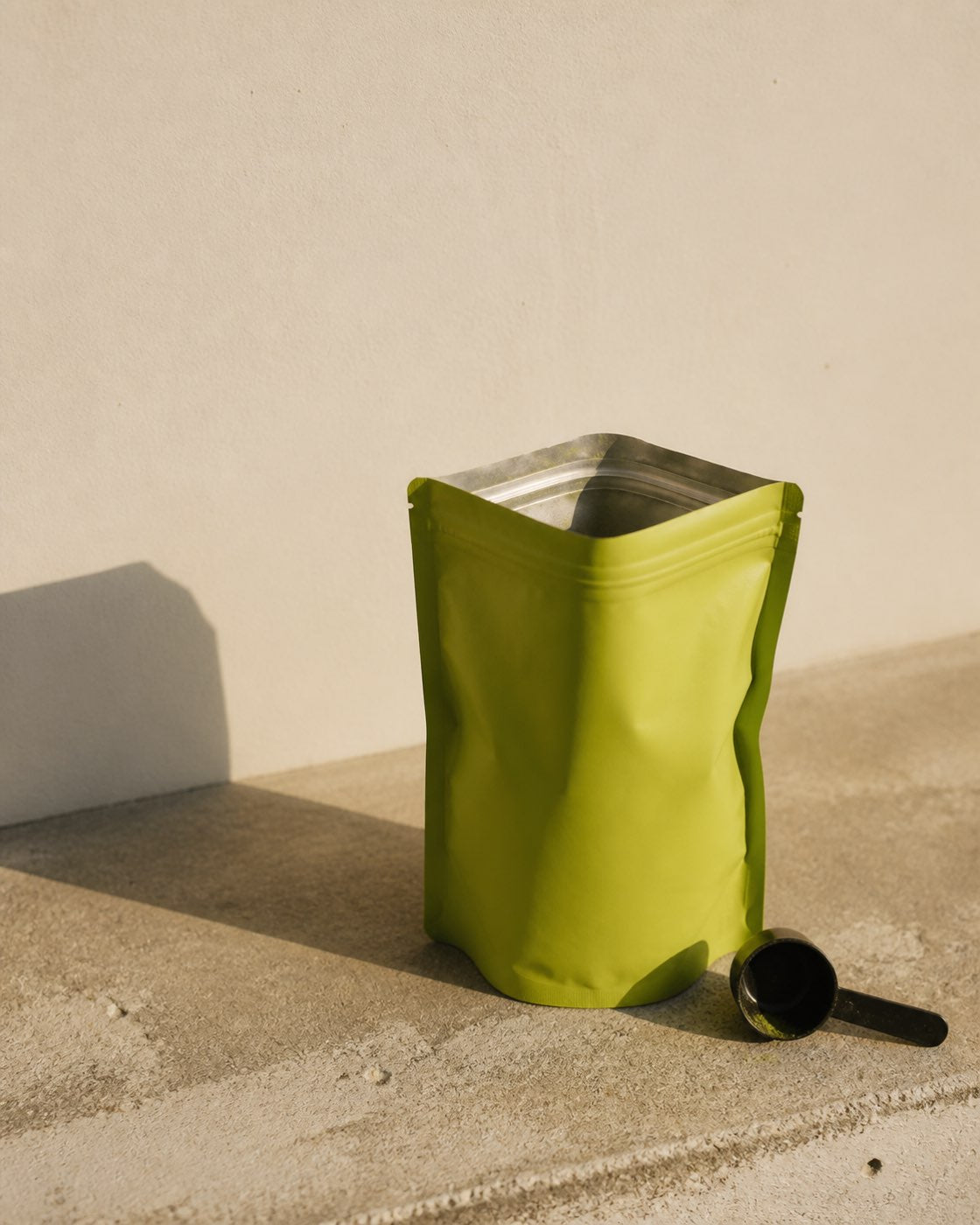 An empty supplement pouch, zip open, standing on a plain surface in even light